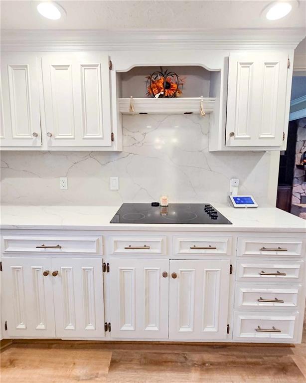 kitchen with black electric cooktop, backsplash, and white cabinetry