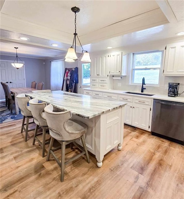 kitchen with a kitchen bar, light wood-type flooring, stainless steel dishwasher, white cabinetry, and a sink