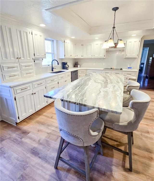 kitchen with light stone countertops, white cabinets, light wood-style floors, a kitchen breakfast bar, and a center island