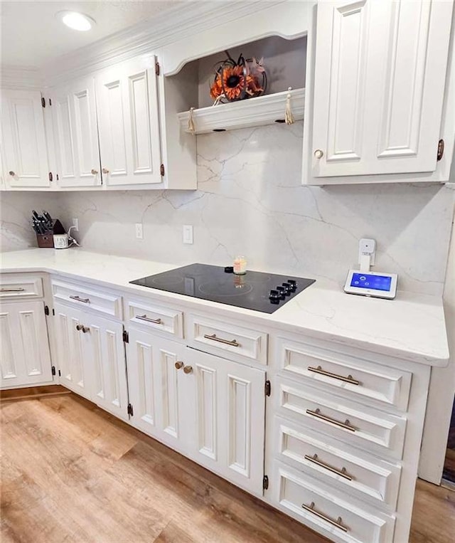 kitchen with light wood-type flooring, black electric stovetop, tasteful backsplash, and white cabinets