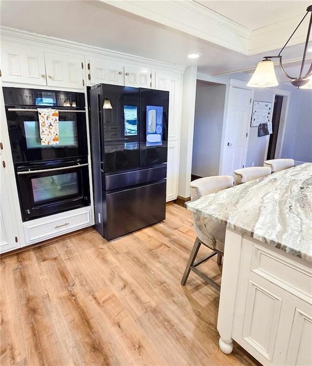 kitchen with light wood-style flooring, white cabinetry, black appliances, and ornamental molding