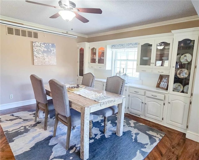 dining area featuring dark wood finished floors, visible vents, ceiling fan, and ornamental molding