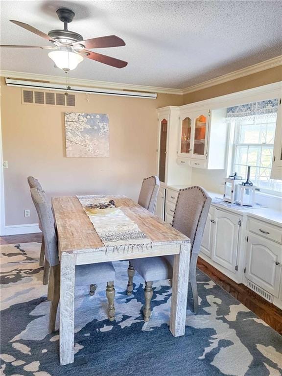 dining room with crown molding, a ceiling fan, visible vents, and a textured ceiling