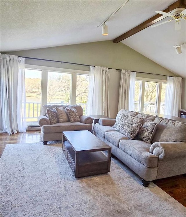 living area featuring a ceiling fan, a textured ceiling, wood finished floors, and vaulted ceiling with beams