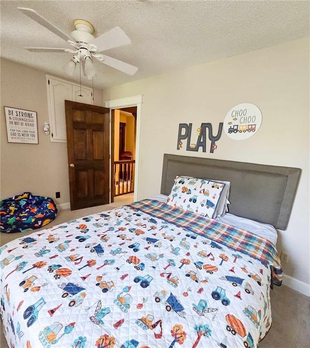 carpeted bedroom featuring baseboards, a textured ceiling, and a ceiling fan