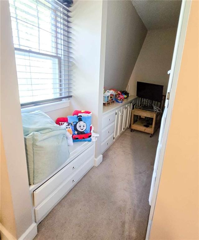 bedroom with light colored carpet and lofted ceiling