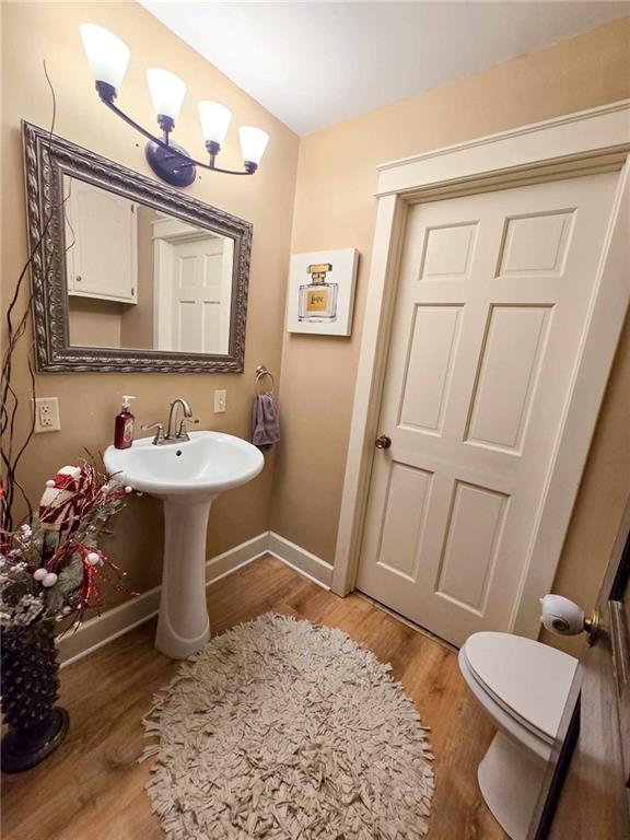 bathroom with toilet, baseboards, and wood finished floors