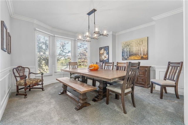 dining space featuring wainscoting, ornamental molding, a notable chandelier, and light colored carpet