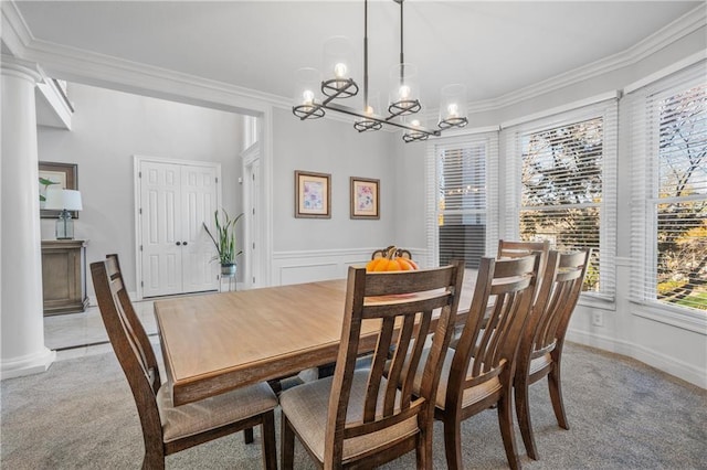 dining area with wainscoting, light colored carpet, crown molding, and decorative columns