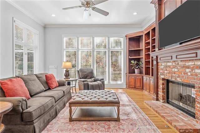 living room with a ceiling fan, crown molding, light wood-type flooring, a fireplace, and recessed lighting