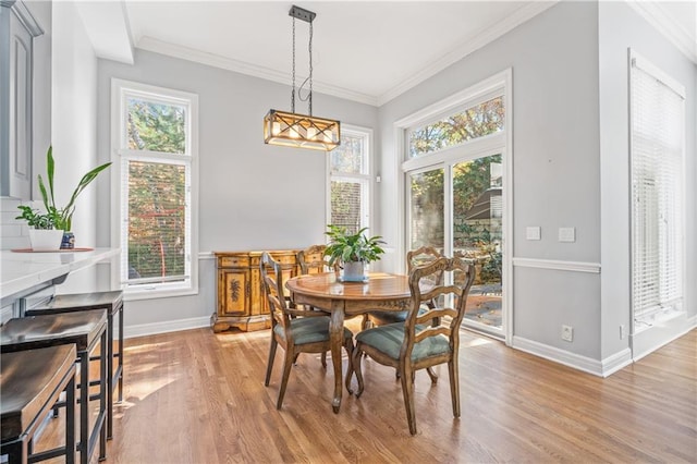 dining space with light wood-type flooring, a healthy amount of sunlight, and crown molding