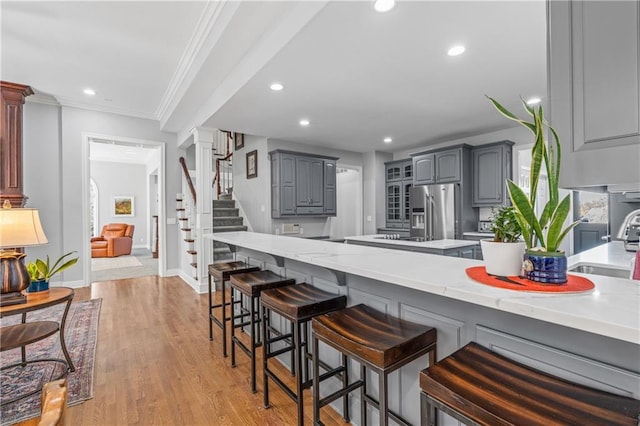 kitchen with decorative columns, gray cabinets, stainless steel refrigerator with ice dispenser, and a sink