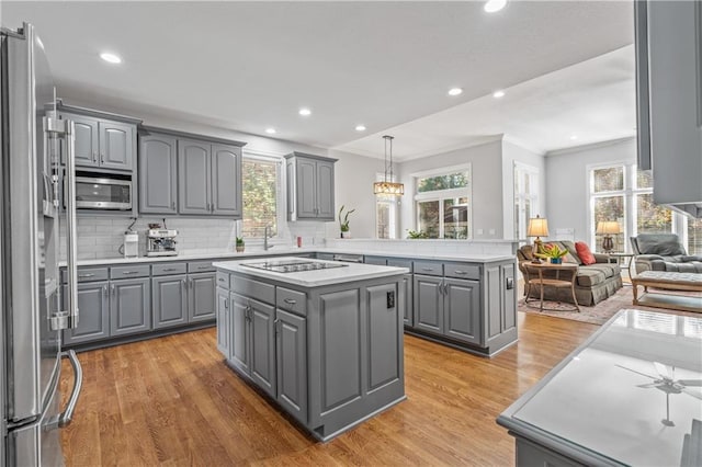 kitchen featuring stainless steel appliances, open floor plan, gray cabinets, and a center island