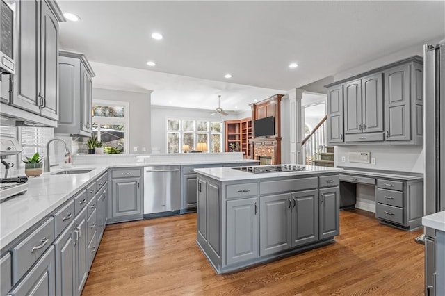 kitchen with a center island, gray cabinetry, wood finished floors, stovetop, and dishwasher