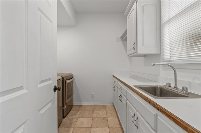 clothes washing area with light tile patterned floors, cabinet space, a sink, washer and dryer, and baseboards