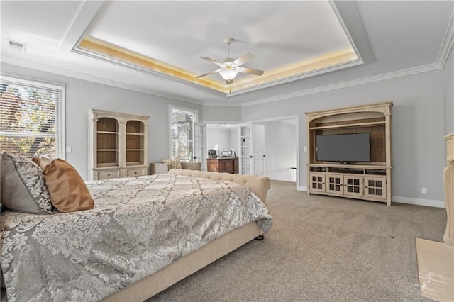 carpeted bedroom with a tray ceiling, visible vents, crown molding, and multiple windows