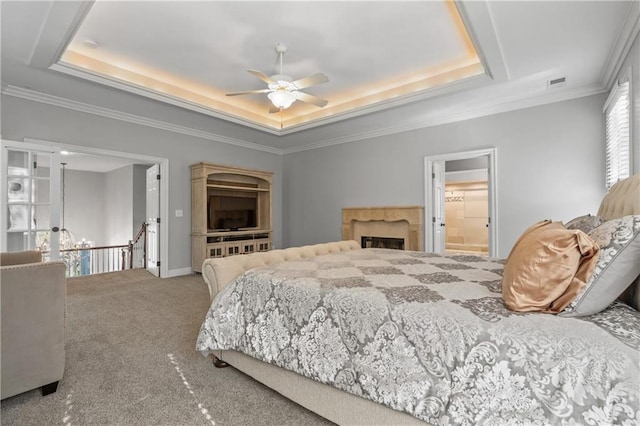 bedroom with carpet flooring, visible vents, a high end fireplace, a tray ceiling, and crown molding