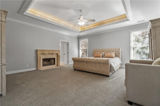 carpeted bedroom featuring multiple windows, visible vents, a raised ceiling, and a fireplace