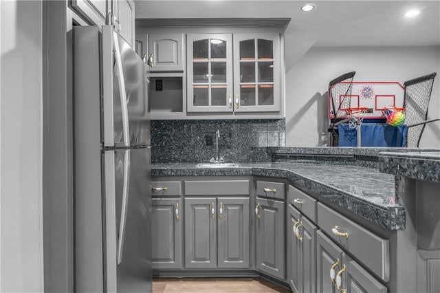 kitchen featuring dark countertops, freestanding refrigerator, and gray cabinetry