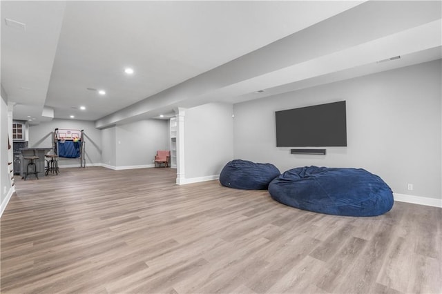 finished basement featuring visible vents, light wood-style flooring, and baseboards