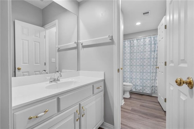 bathroom with curtained shower, toilet, wood finished floors, visible vents, and vanity