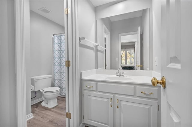 bathroom with visible vents, toilet, vanity, wood finished floors, and baseboards