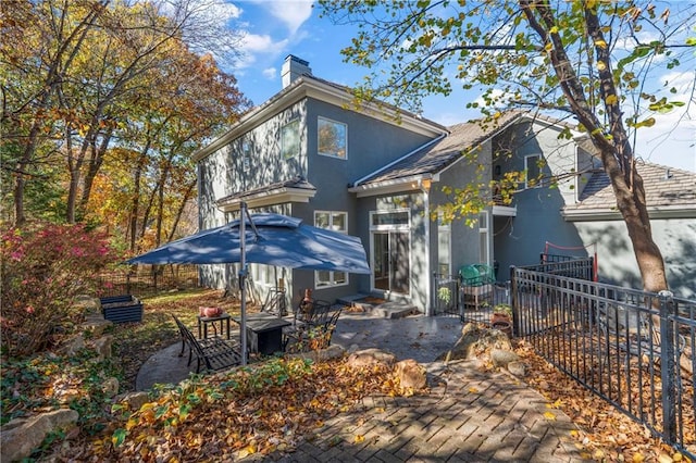 back of house with a patio area, a chimney, fence, and stucco siding