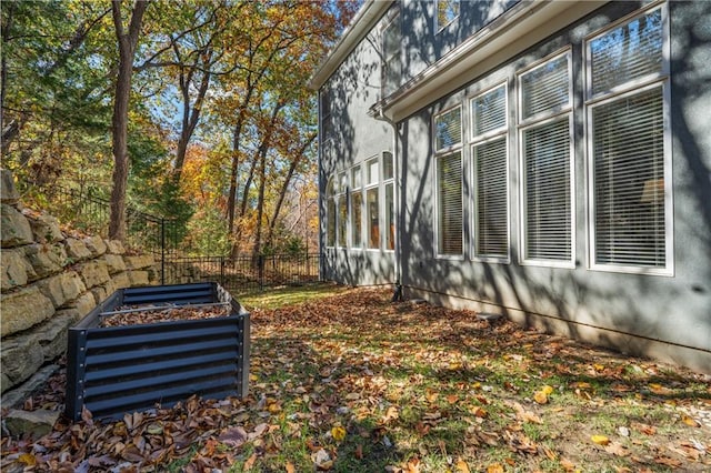 view of side of property featuring a garden and fence