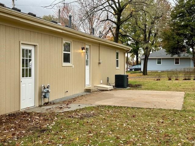 rear view of house with central air condition unit, a patio area, and a yard