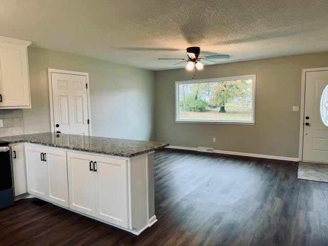 kitchen featuring white cabinets, dark stone countertops, a textured ceiling, and dark wood-type flooring