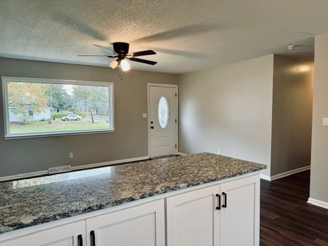 kitchen with dark stone countertops, white cabinets, a textured ceiling, and dark wood-type flooring