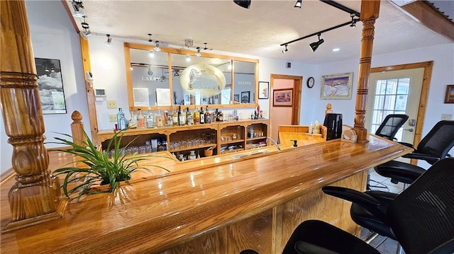 interior space with bar area, a textured ceiling, and track lighting