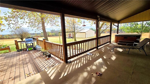 wooden terrace featuring a hot tub, a storage unit, and grilling area