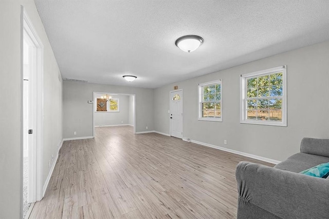 living room with a notable chandelier, a textured ceiling, and light wood-type flooring