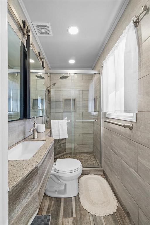 bathroom with hardwood / wood-style flooring, toilet, ornamental molding, a shower with shower door, and vanity