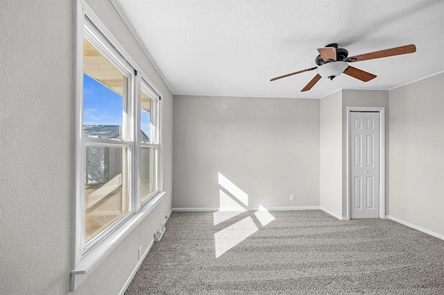 empty room with ceiling fan, carpet flooring, and a textured ceiling