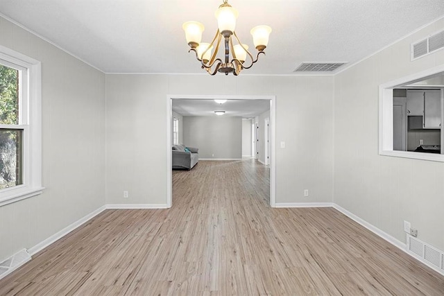 unfurnished dining area featuring ornamental molding, a chandelier, and light hardwood / wood-style floors