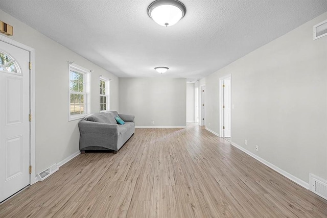 unfurnished room with a textured ceiling, light hardwood / wood-style flooring, and a wealth of natural light