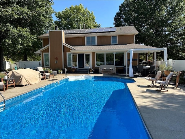 rear view of property featuring solar panels, a patio area, a fenced in pool, and an outdoor living space