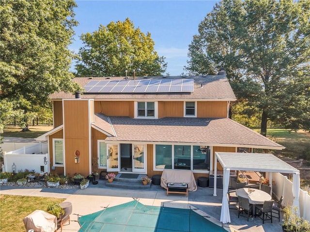 rear view of house with solar panels, a patio area, an outdoor hangout area, and a covered pool