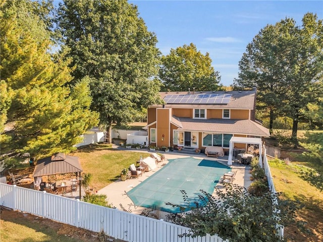 back of house with a lawn, solar panels, a patio area, and a covered pool