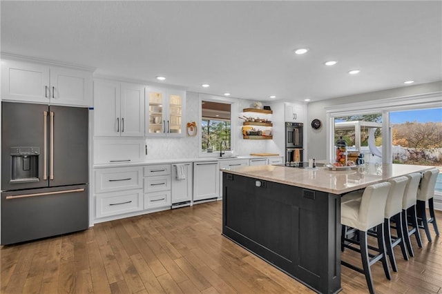 kitchen with a wealth of natural light, light wood-type flooring, white cabinetry, and appliances with stainless steel finishes