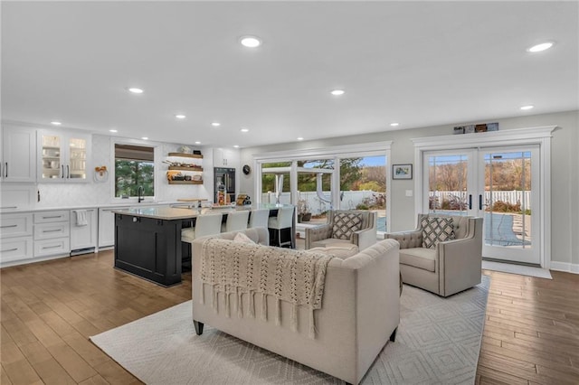 living room with french doors, sink, and light hardwood / wood-style flooring