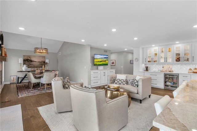 living room featuring indoor bar, hardwood / wood-style flooring, vaulted ceiling, and beverage cooler