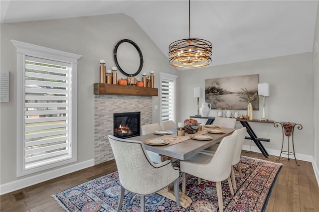 dining space with an inviting chandelier, dark wood-type flooring, and vaulted ceiling