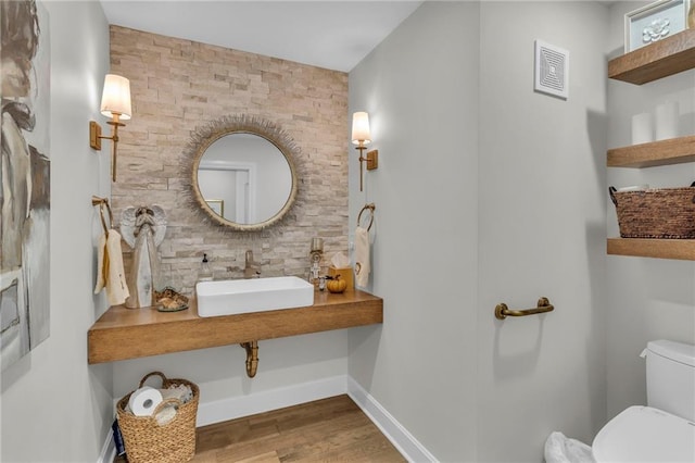 bathroom featuring toilet, sink, and hardwood / wood-style flooring