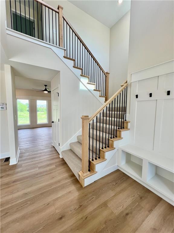7709 NE 106th Pl, Kansas City, MO 64157 - stairs featuring a towering ceiling, wood finished floors, and ceiling fan