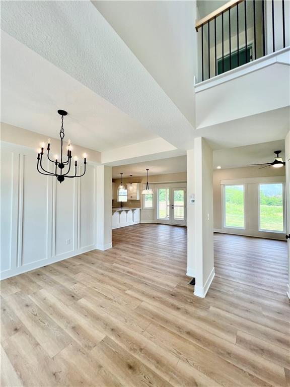 7709 NE 106th Pl, Kansas City, MO 64157 - unfurnished living room with light wood finished floors, a chandelier, and ceiling fan