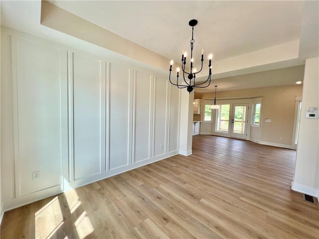 7709 NE 106th Pl, Kansas City, MO 64157 - unfurnished dining area featuring a chandelier, light wood finished floors, a tray ceiling, and a decorative wall