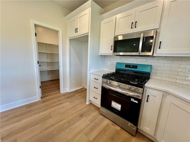 7709 NE 106th Pl, Kansas City, MO 64157 - kitchen featuring appliances with stainless steel finishes, light wood-style flooring, light countertops, and backsplash